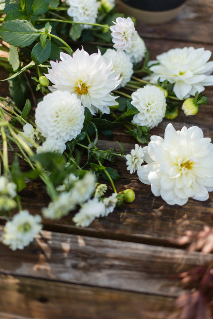 Image of white flowers resting on a wooden table for the Floral Installation Setup with The Floral Coach