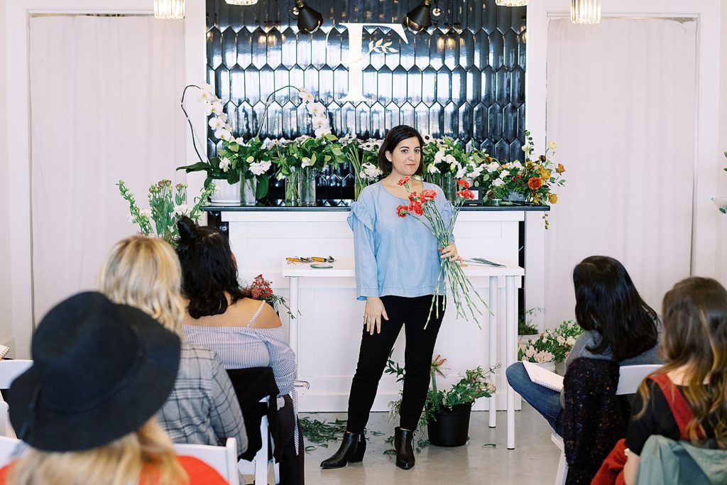 Amy from Amy Nicole Floral stands in front of her workshop students as she prepares to talk about how to press flowers: repurposing a bouquet.