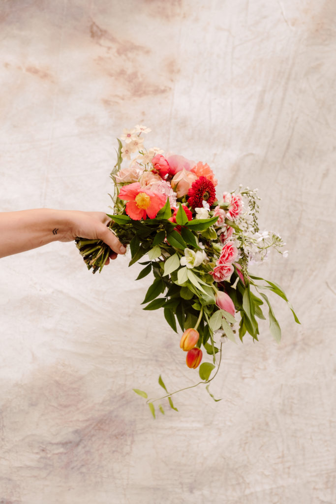 Hand holding up one of the stunning floral arrangements from Amy Balsters' floral arrangement class; photo by @karenobrist