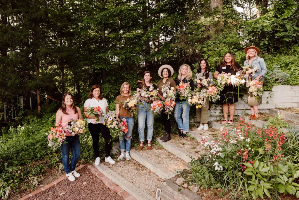 Eight florists stand in line with Amy Balsters from The Floral Coach while showcasing their floral arrangements; photo by @karenobrist