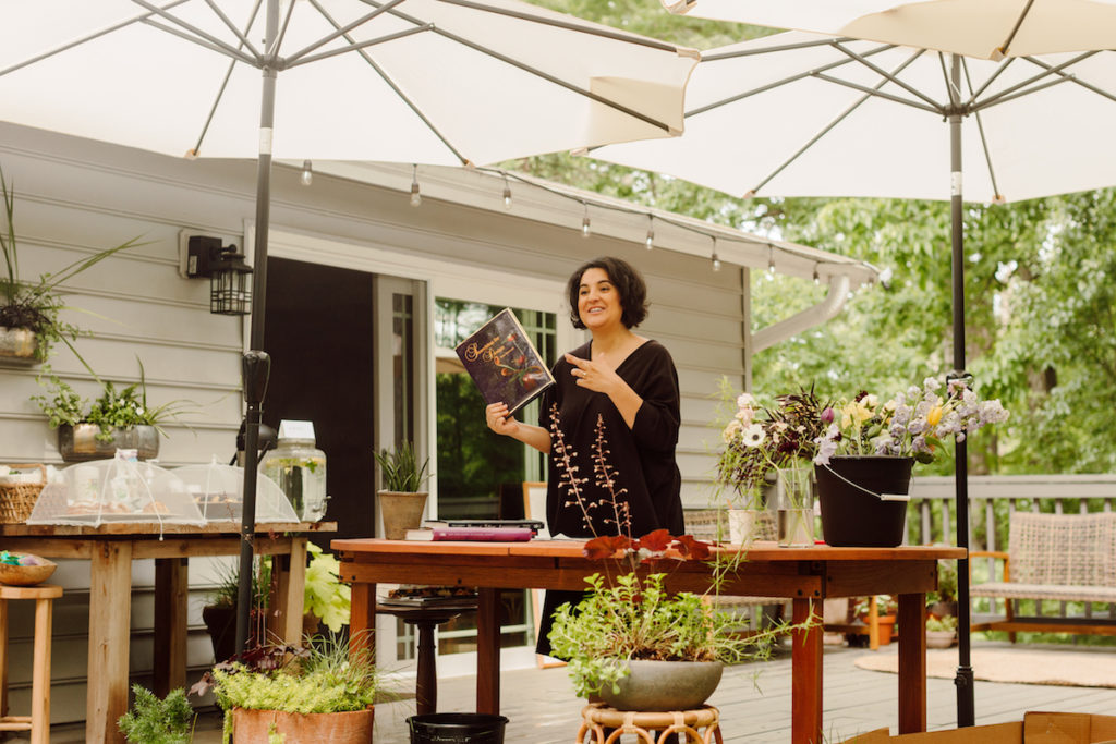 Amy Balsters from The Floral Coach holding up a book while having a floral arrangement class; photo by @karenobrist