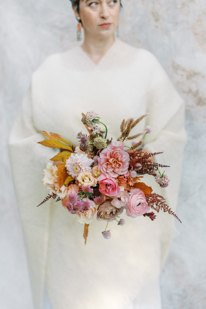 A bride holds a beautiful pink, blush, and lavender bouquet